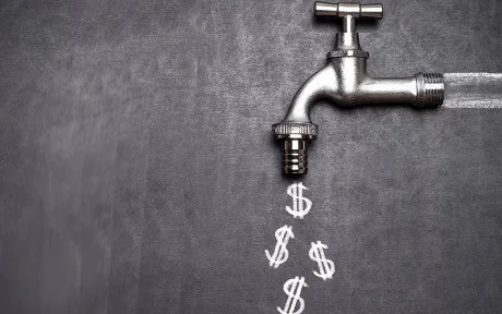 Decorative photo of silver spigot on blackboard with dollar signs chalked on the board coming out of the spigot.
