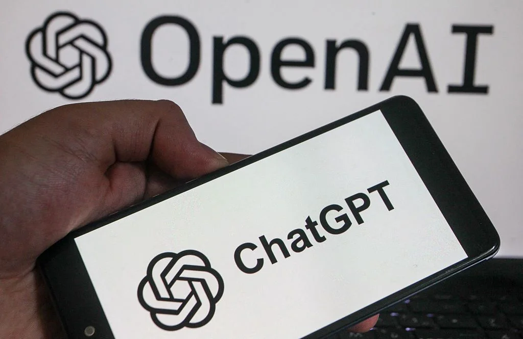 A smartphone displaying the logos of US technology company OpenAI and its artificial intelligence assistant ChatGPT held in a hand.